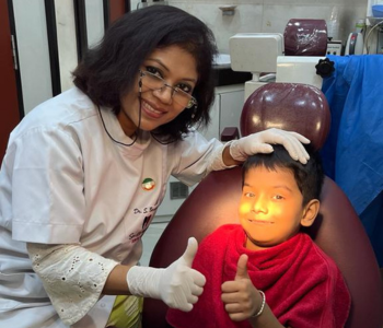 Dr Sawon posing with child patient at smile signature